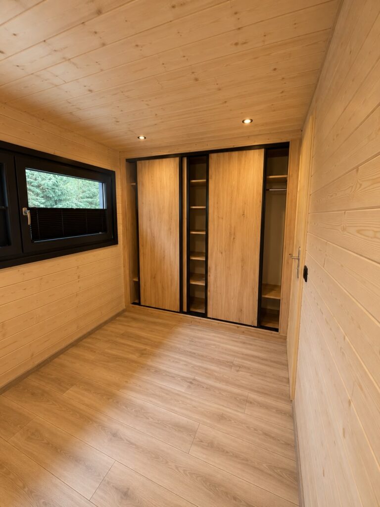 Sypialnia wykończona naturalnym drewnem w domku modułowym Modular 2