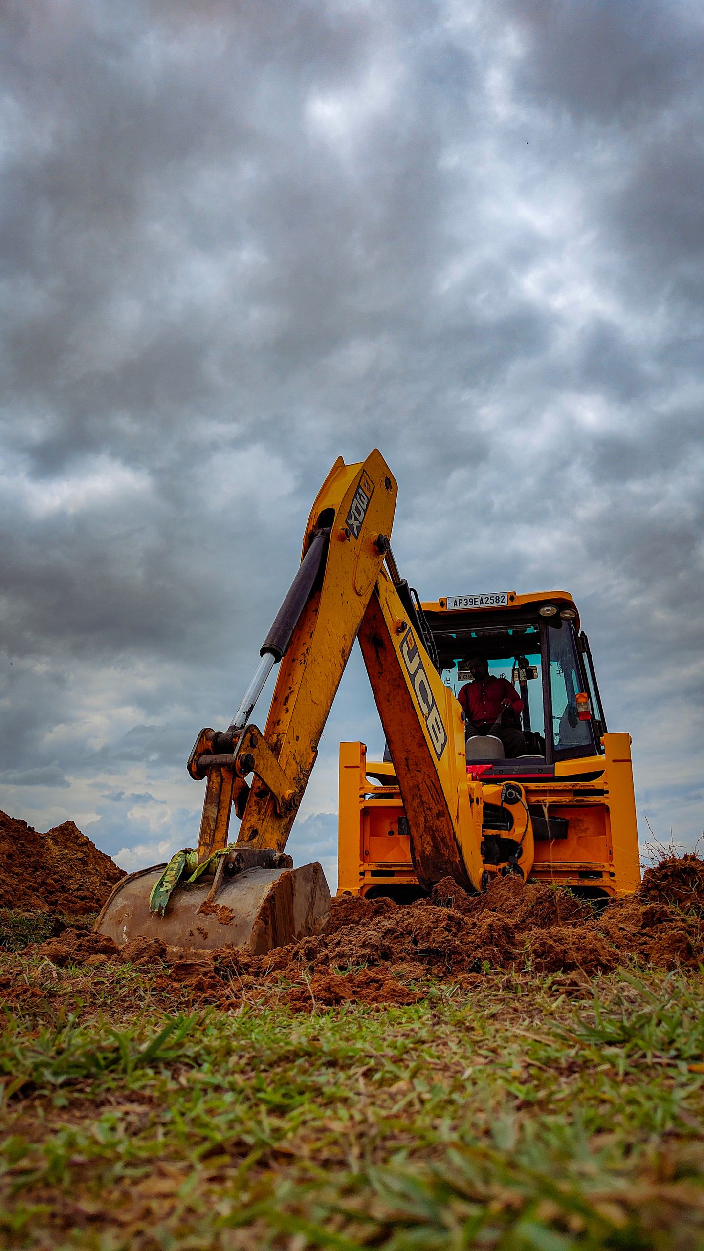 przygotowanie gruntu Yellow bulldozer working on a grassy field under cloudy skies.